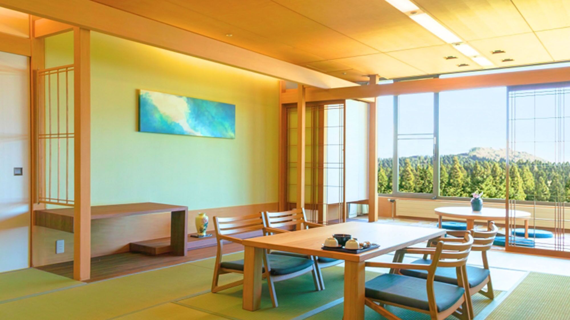 Une pièce de style japonais traditionnel, avec un sol recouvert de tatamis, une table basse et une vue sur une montagne boisée.