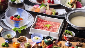 A variety of Japanese dishes including sushi, sashimi, and a hot pot, arranged on a wooden table.