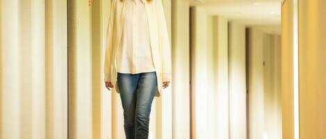 A person walking down a corridor with a ceiling that has recessed lighting and ventilation panels.