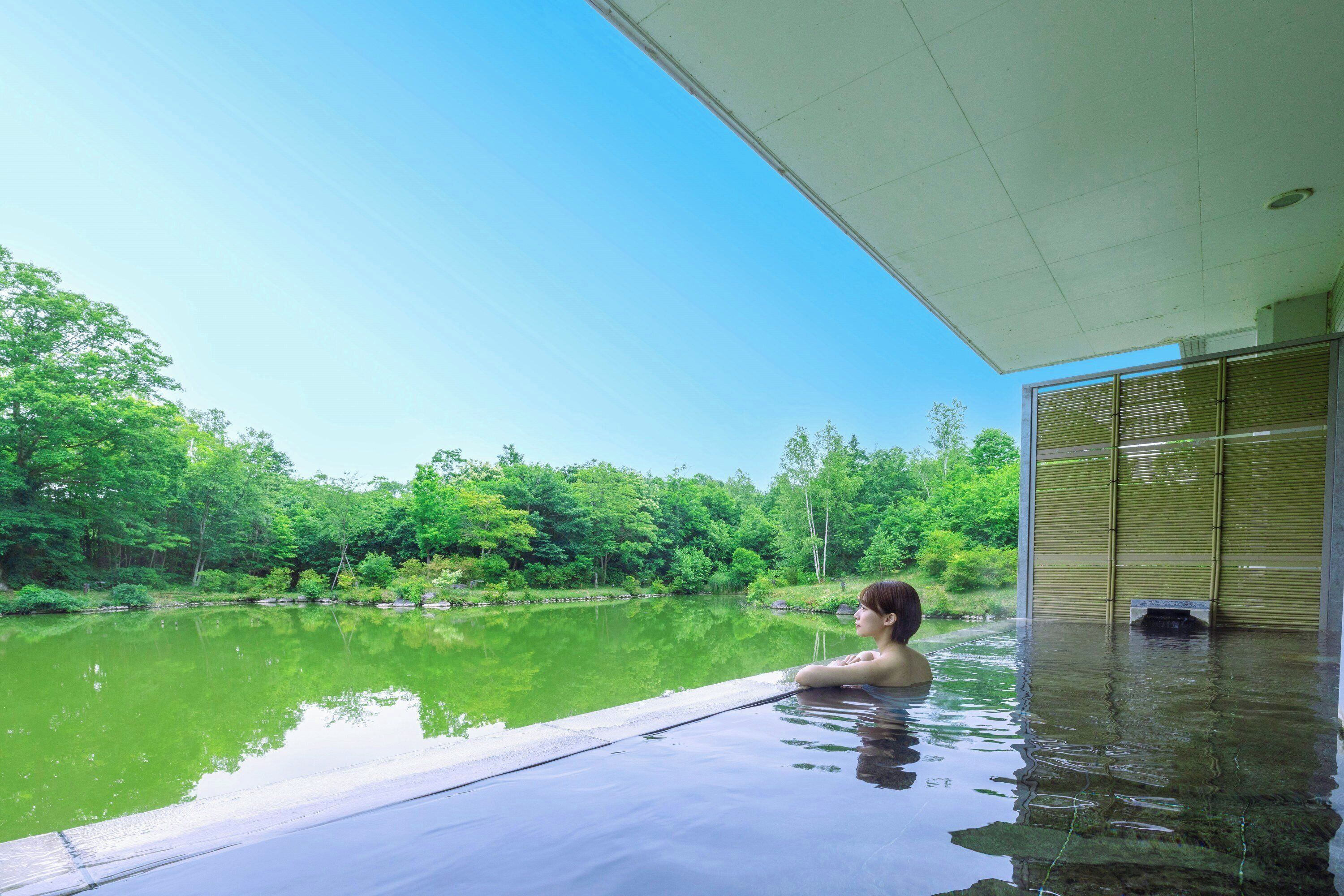 A person relaxing in a pool with a view of a forested area.