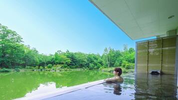 A person relaxing in a pool with a view of a forested area.
