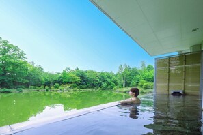 A person relaxing in a pool with a view of a forested area.