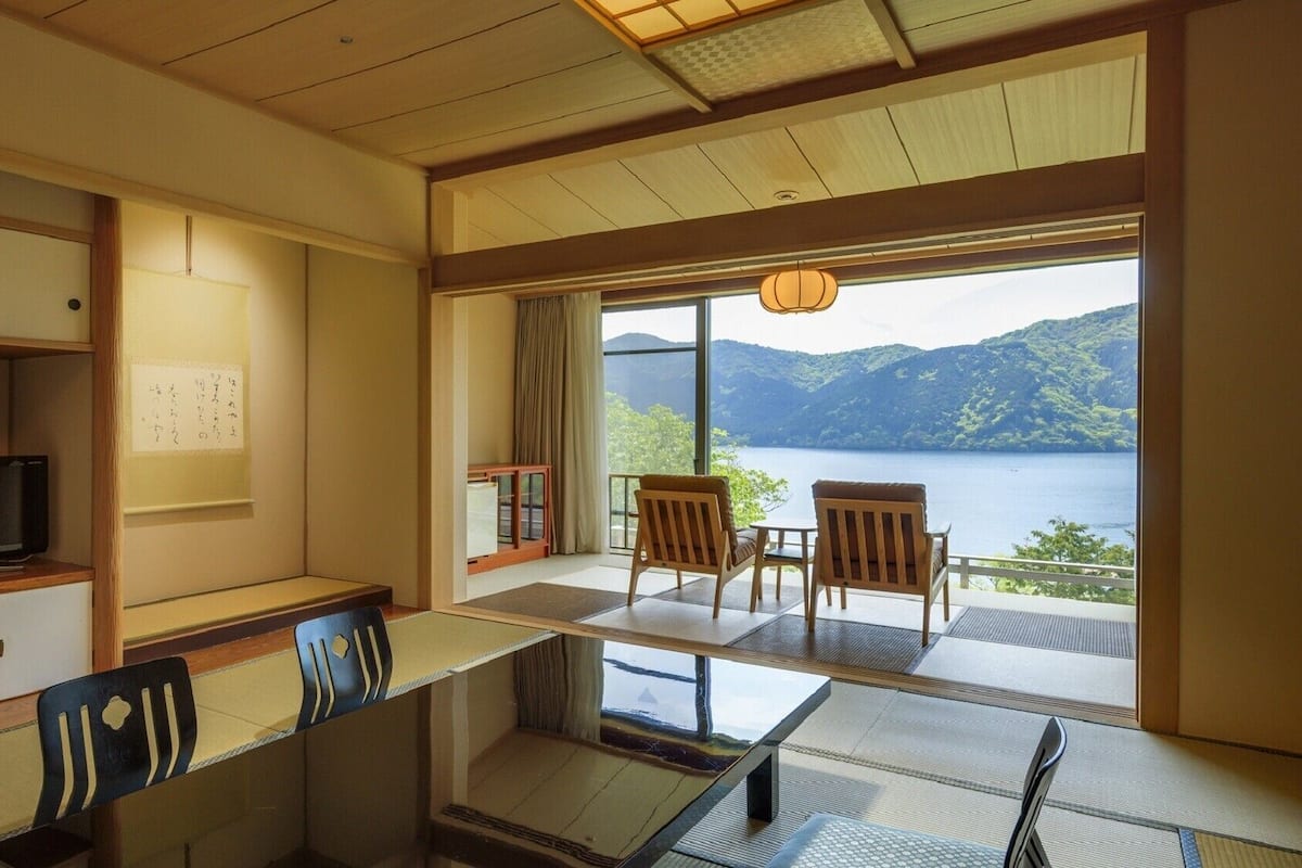A room with tatami mats, a television, a desk, and chairs.