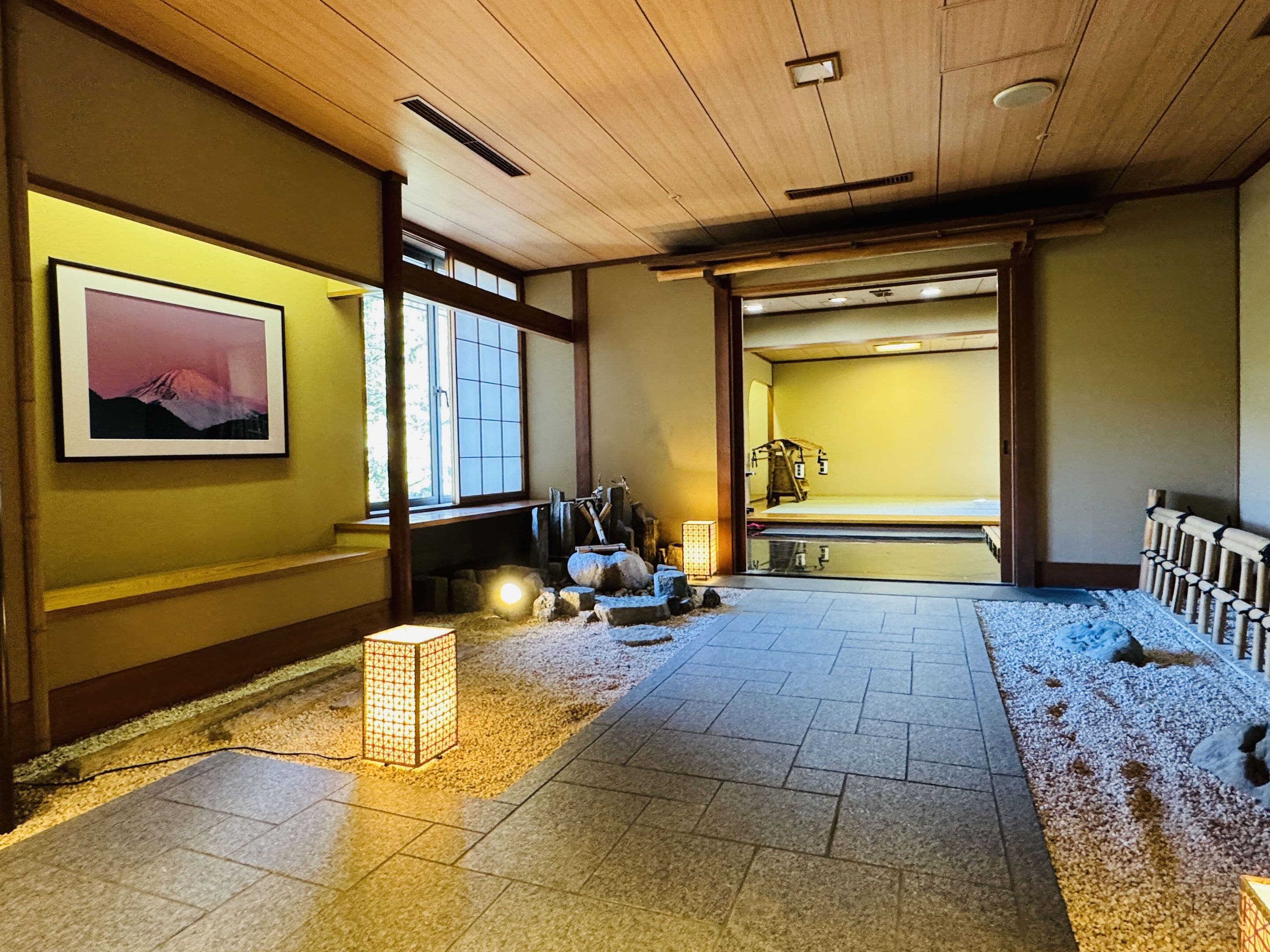 A traditional Japanese room with tatami flooring, a shoji screen door, and a low wooden ceiling.