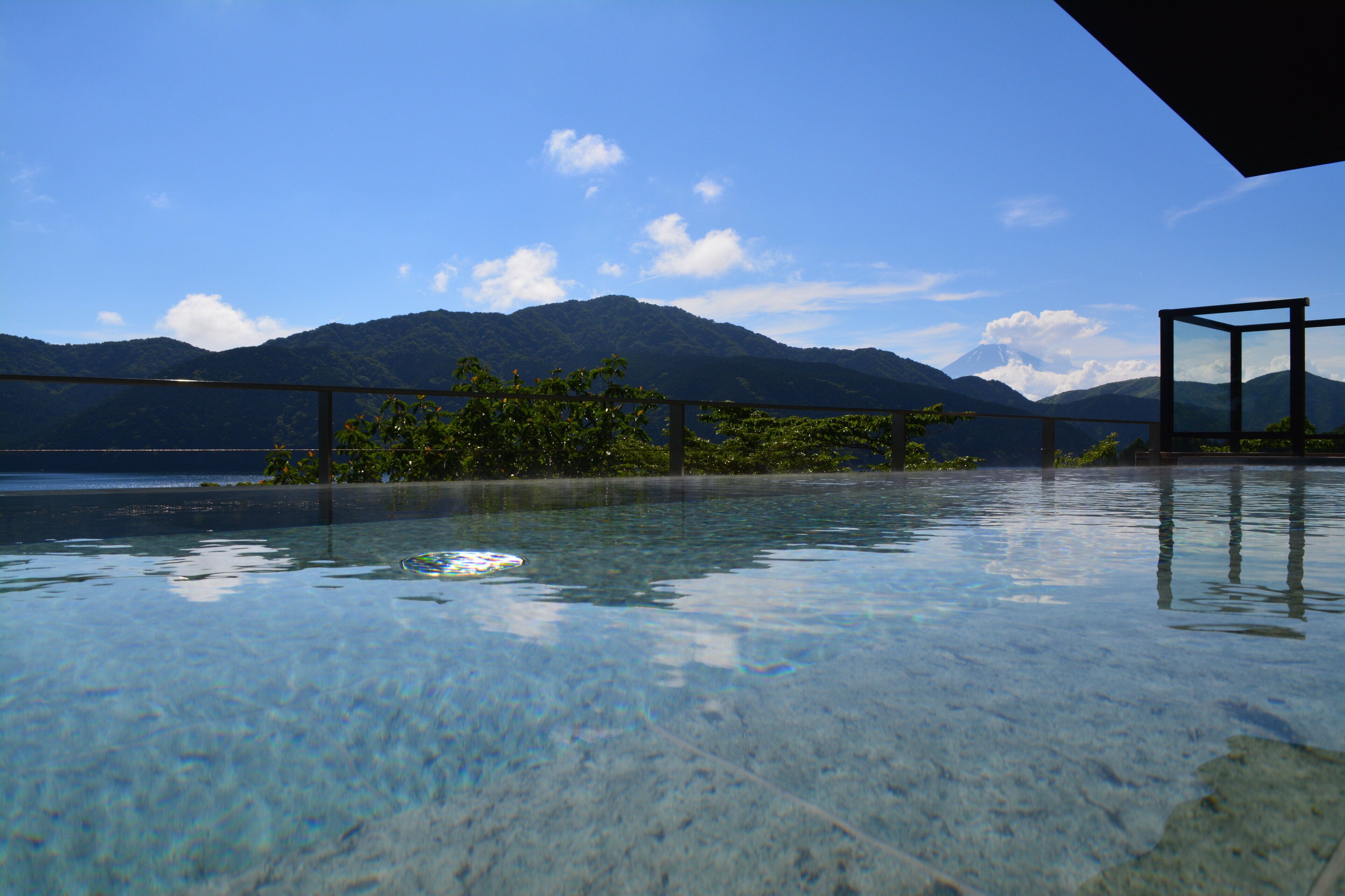 An infinity pool with a clear view of mountains and a body of water.