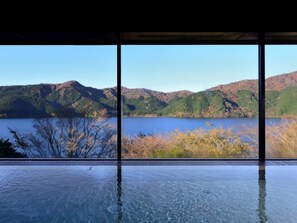 A clear view of a lake with mountains in the background through large windows. - Ryuguden (Hakone)