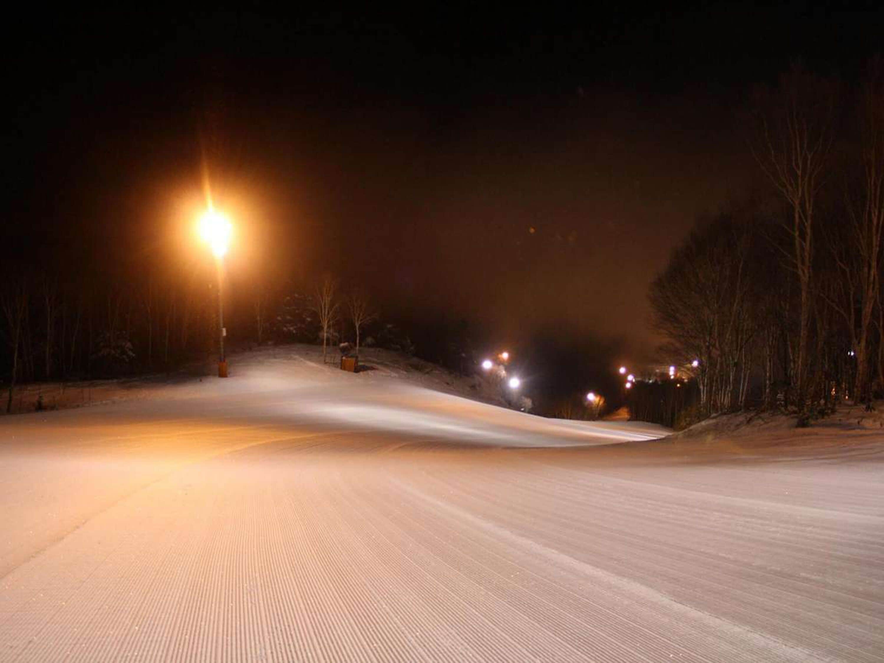 A snow-covered road at night with streetlights.