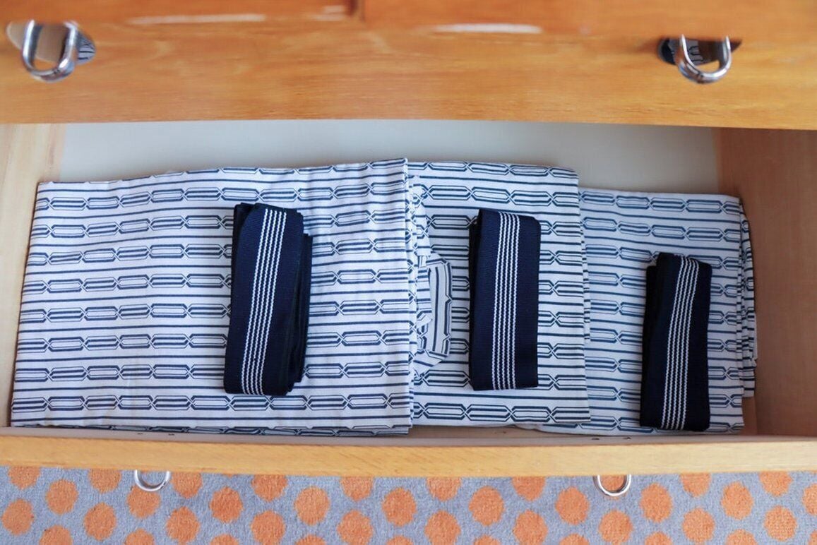 A drawer with neatly folded striped shirts and ties.