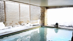 An indoor swimming pool with stone walls and a tiled floor.