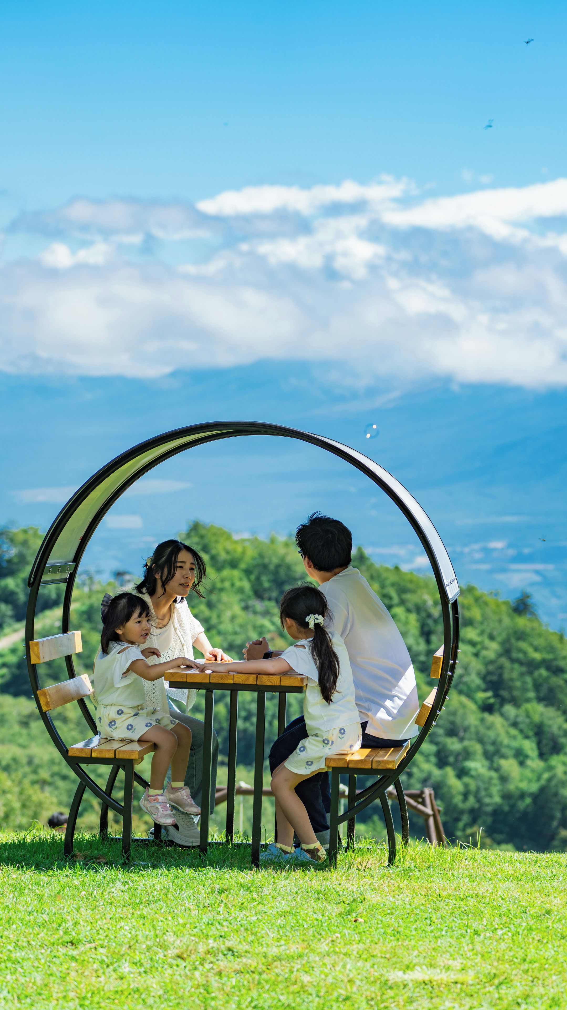 Un grupo de personas sentadas en una mesa al aire libre con una vista panorámica de fondo.