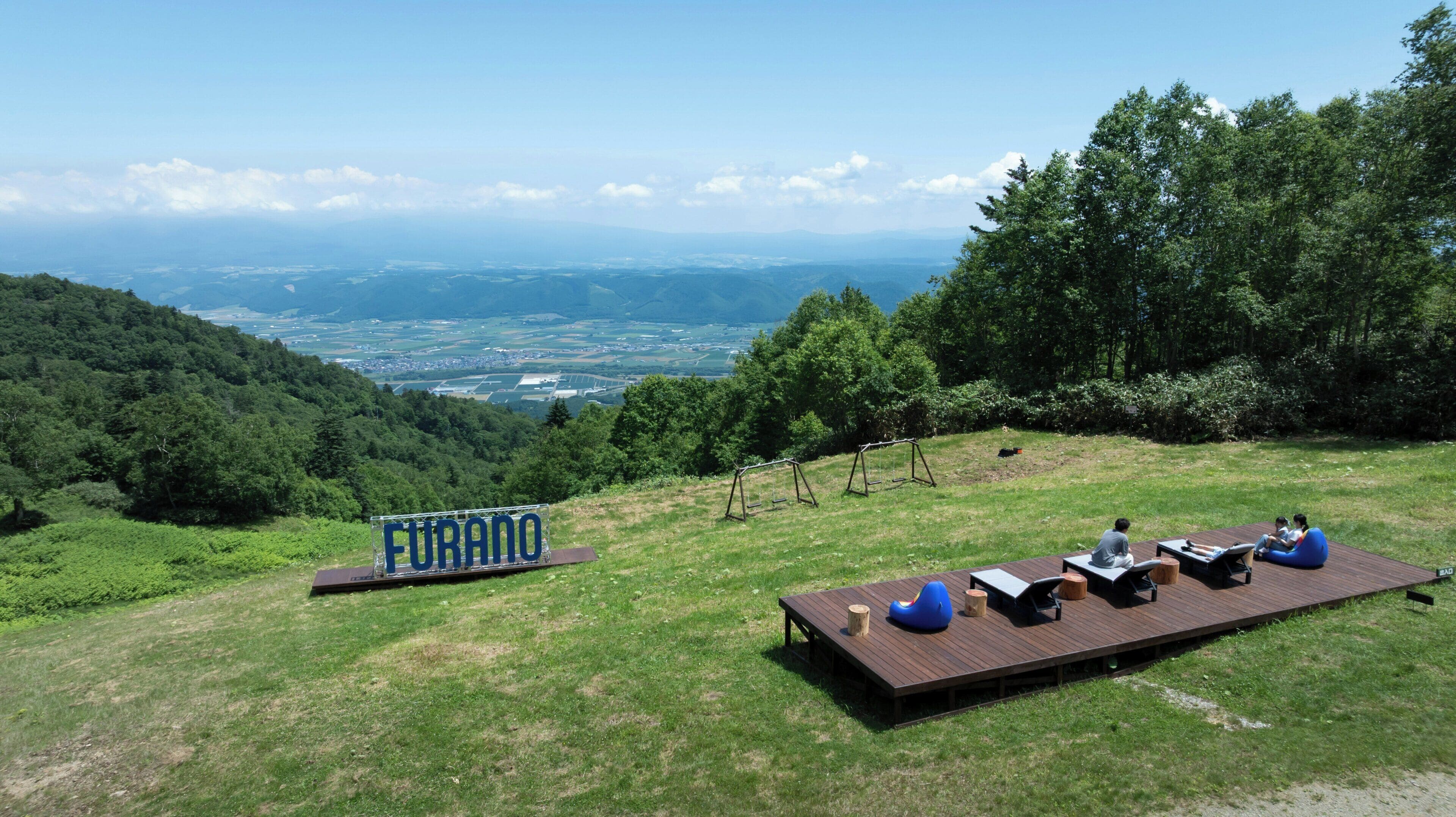 A deck with seating and a sign reading 'Furano' overlooking a scenic landscape.
