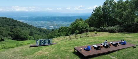 A deck with seating and a sign reading 'Furano' overlooking a scenic landscape.