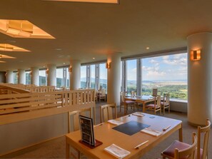 Ein Hotel-Speisesaal mit hohen Decken, großen Fenstern und Blick auf die Landschaft.