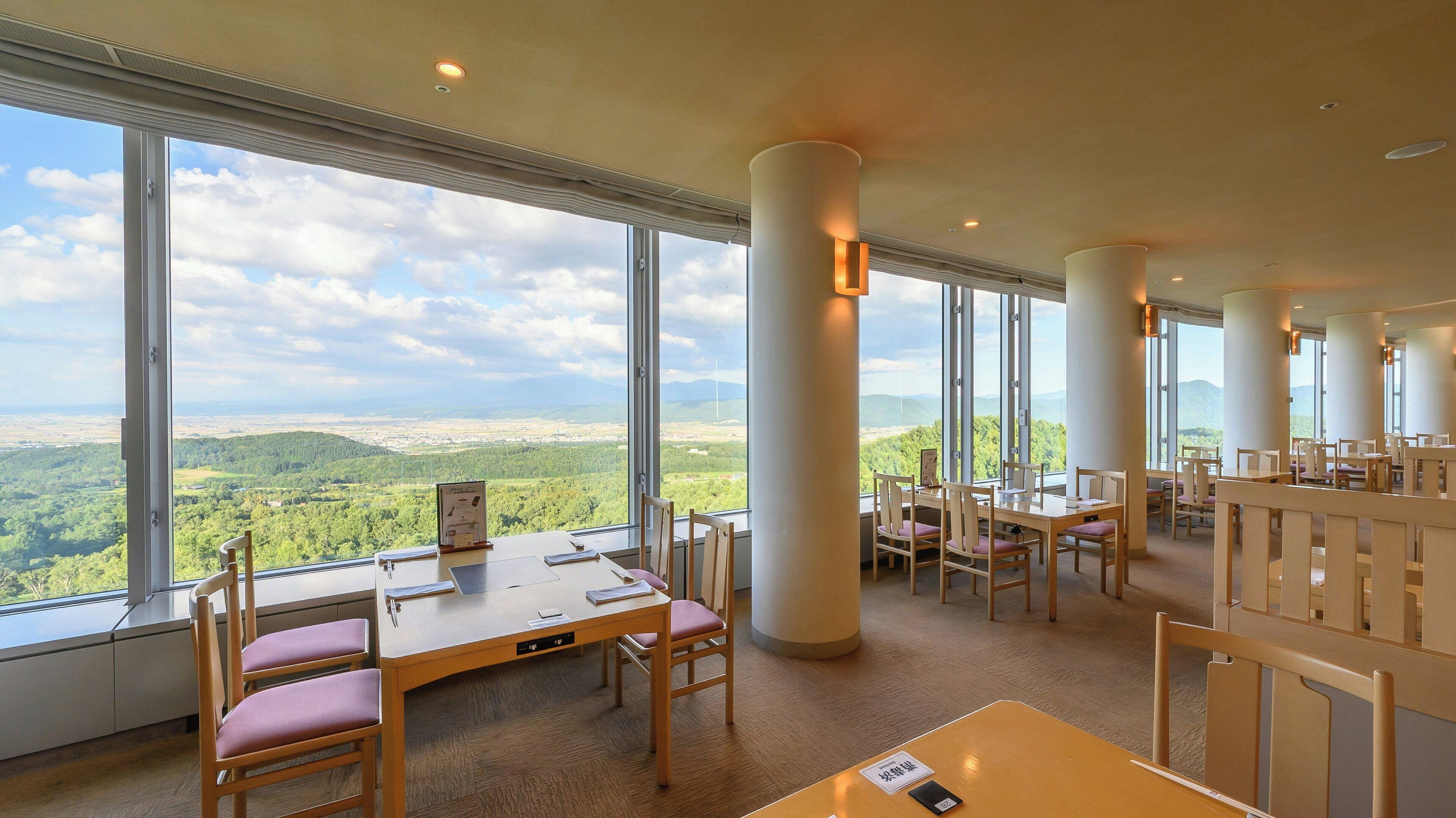 A spacious room with large windows offering a panoramic view of the landscape.