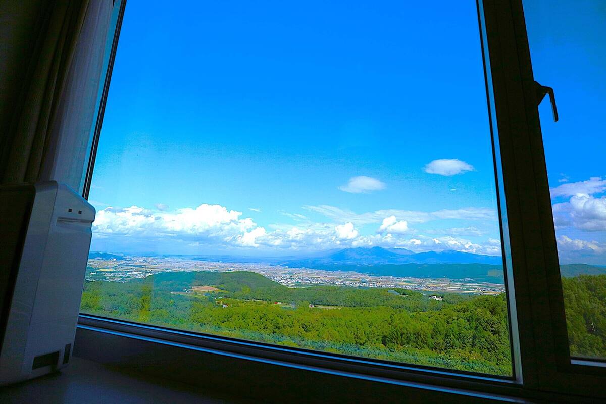 Vista pela janela, com céu limpo e paisagem distante.