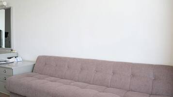 A neutral-toned room with a sofa, a small bedside table, and a mirror.