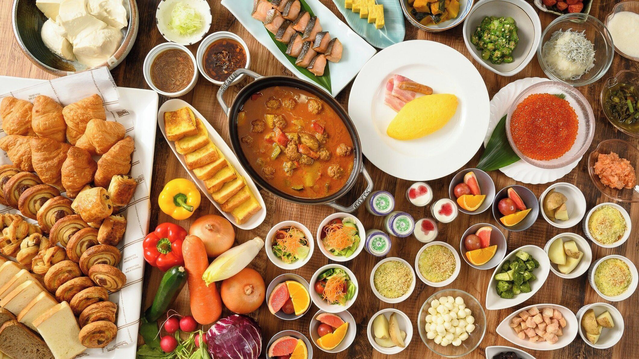 A variety of food items and pastries arranged on a wooden table.