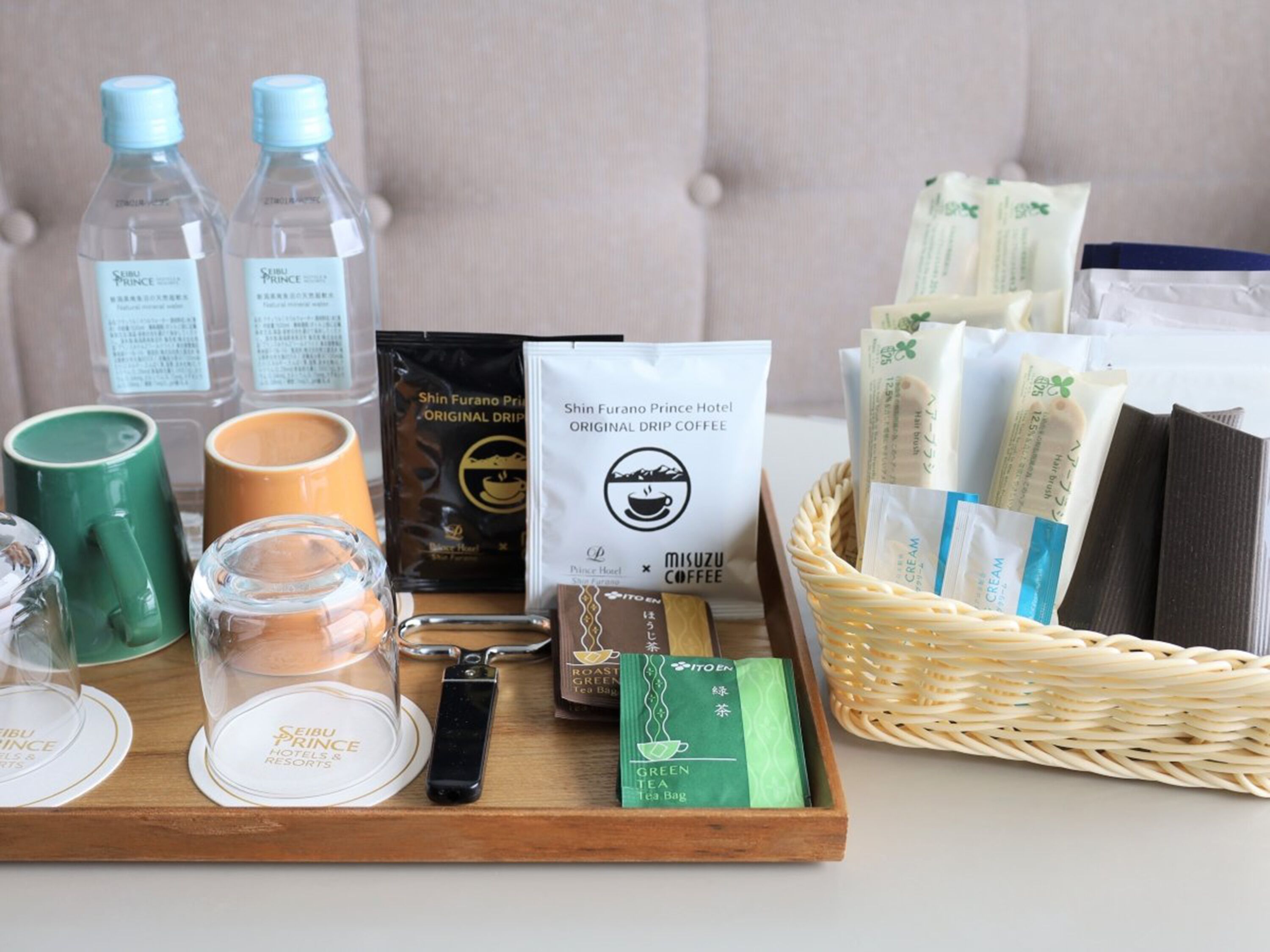 A tray with various items including bottled water, coffee, tea bags, and a tea bag with a green label.