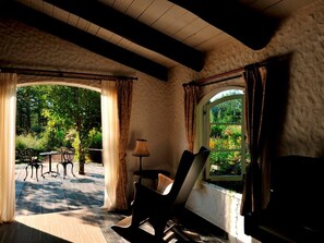 Ein Zimmer mit Blick auf einen Garten, ein Tisch mit Stühlen, eine Lampe und ein Fernseher.