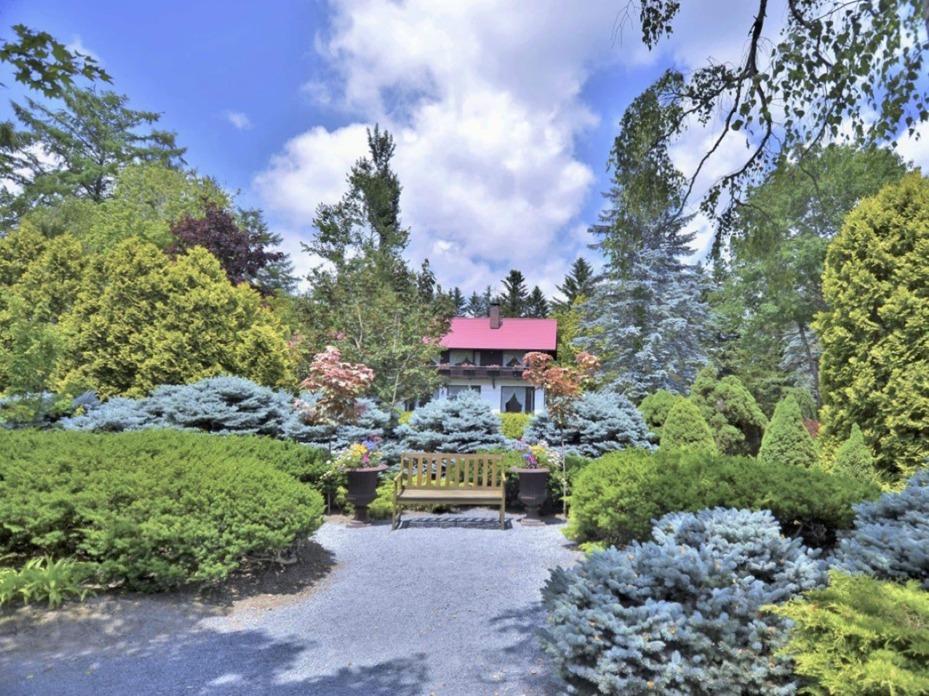 A building with a red roof, surrounded by well-maintained gardens and trees.