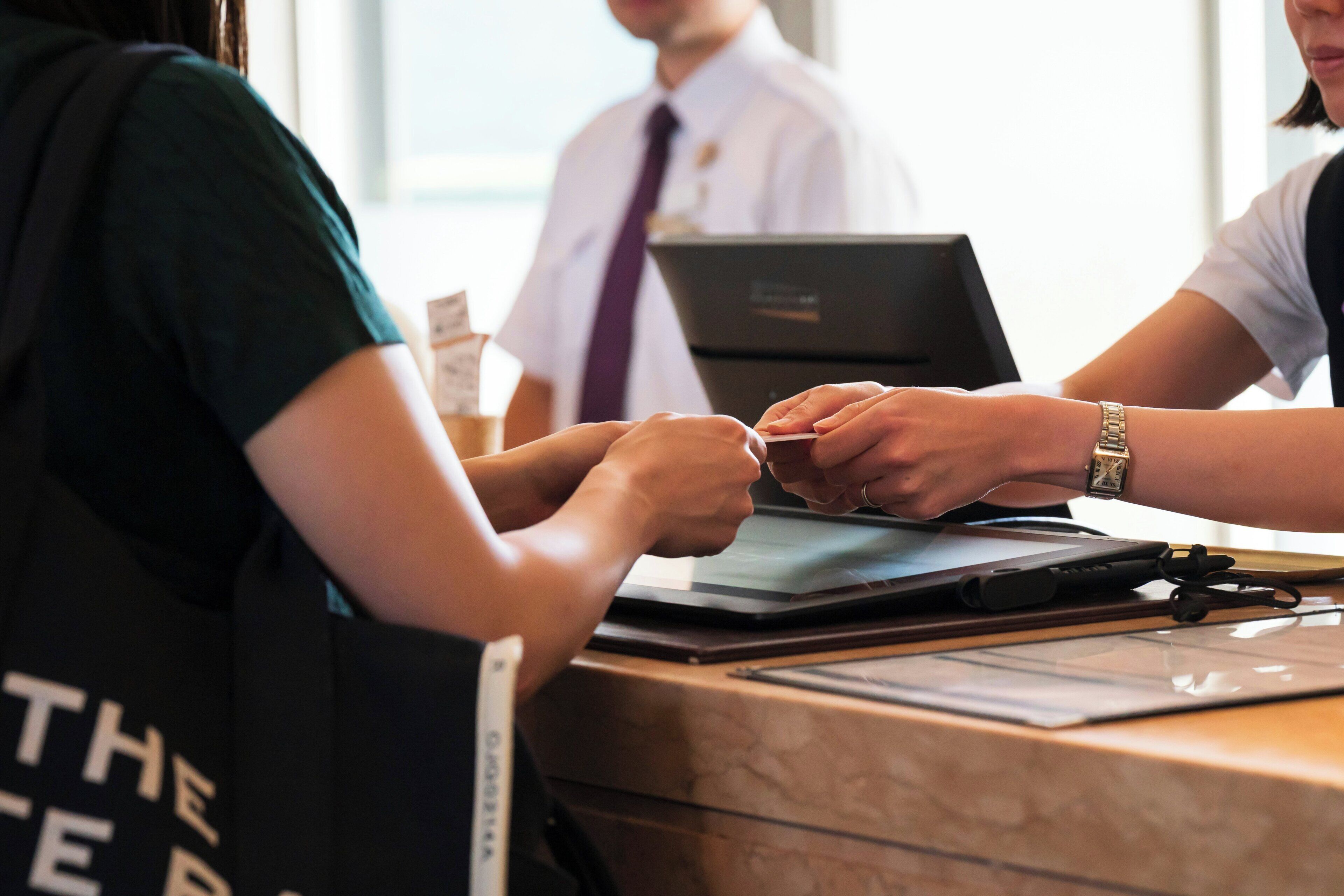 A reception desk with a laptop, a tablet, and a pen.