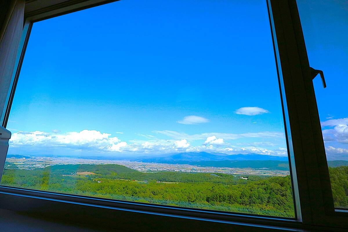 Janela com vista ampla da paisagem, incluindo um corpo d'água e montanhas ao longe.
