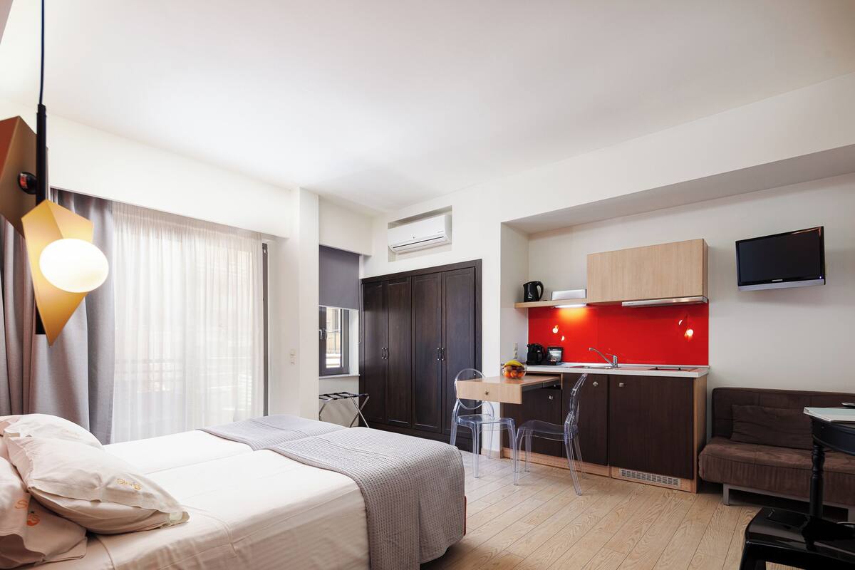Une chambre d’hôtel moderne équipée d’un lit, d’un bureau, d’une kitchenette et d’un téléviseur.