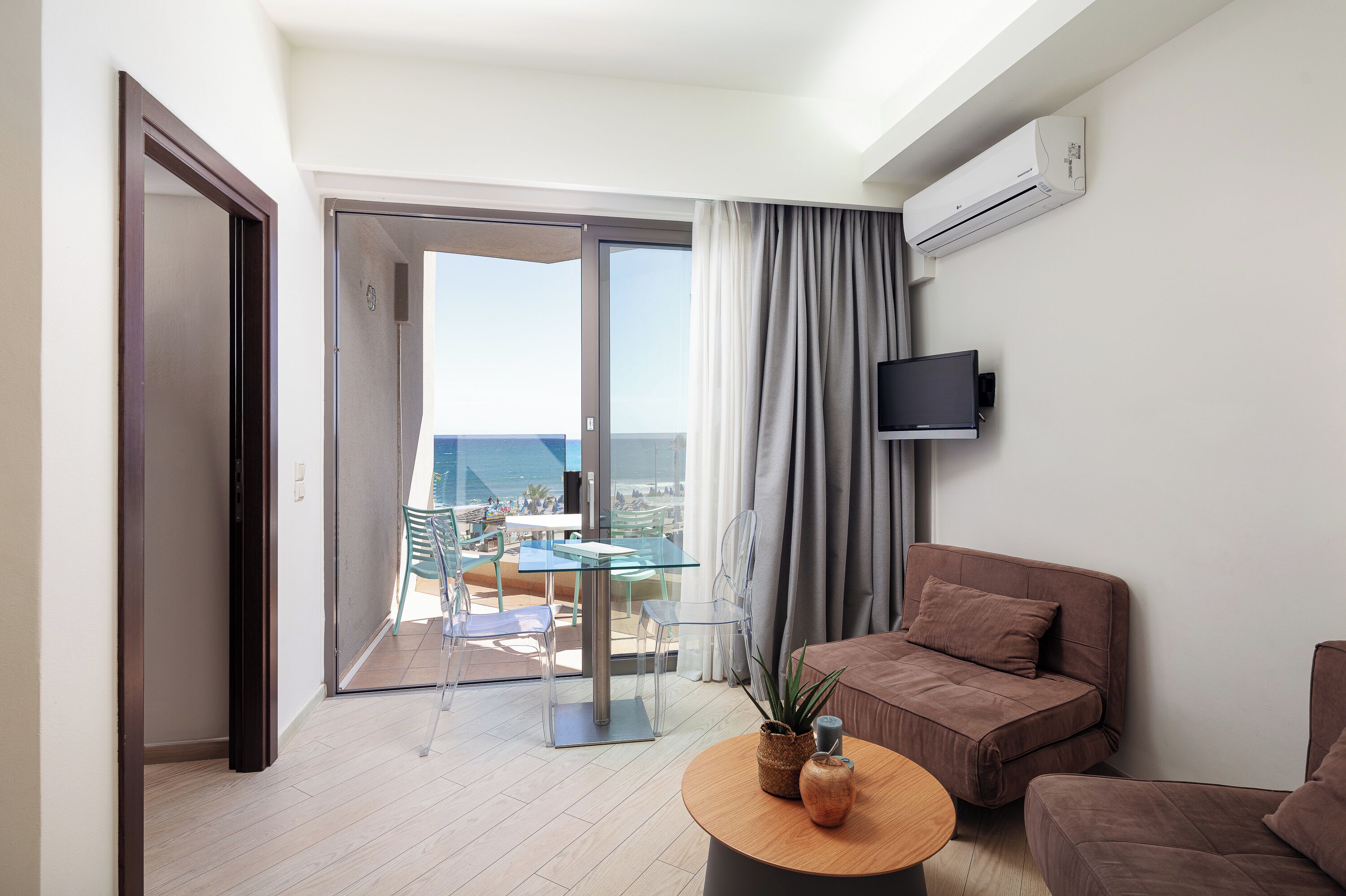 A modern living room with a balcony, a flat-screen TV, and a wooden coffee table.