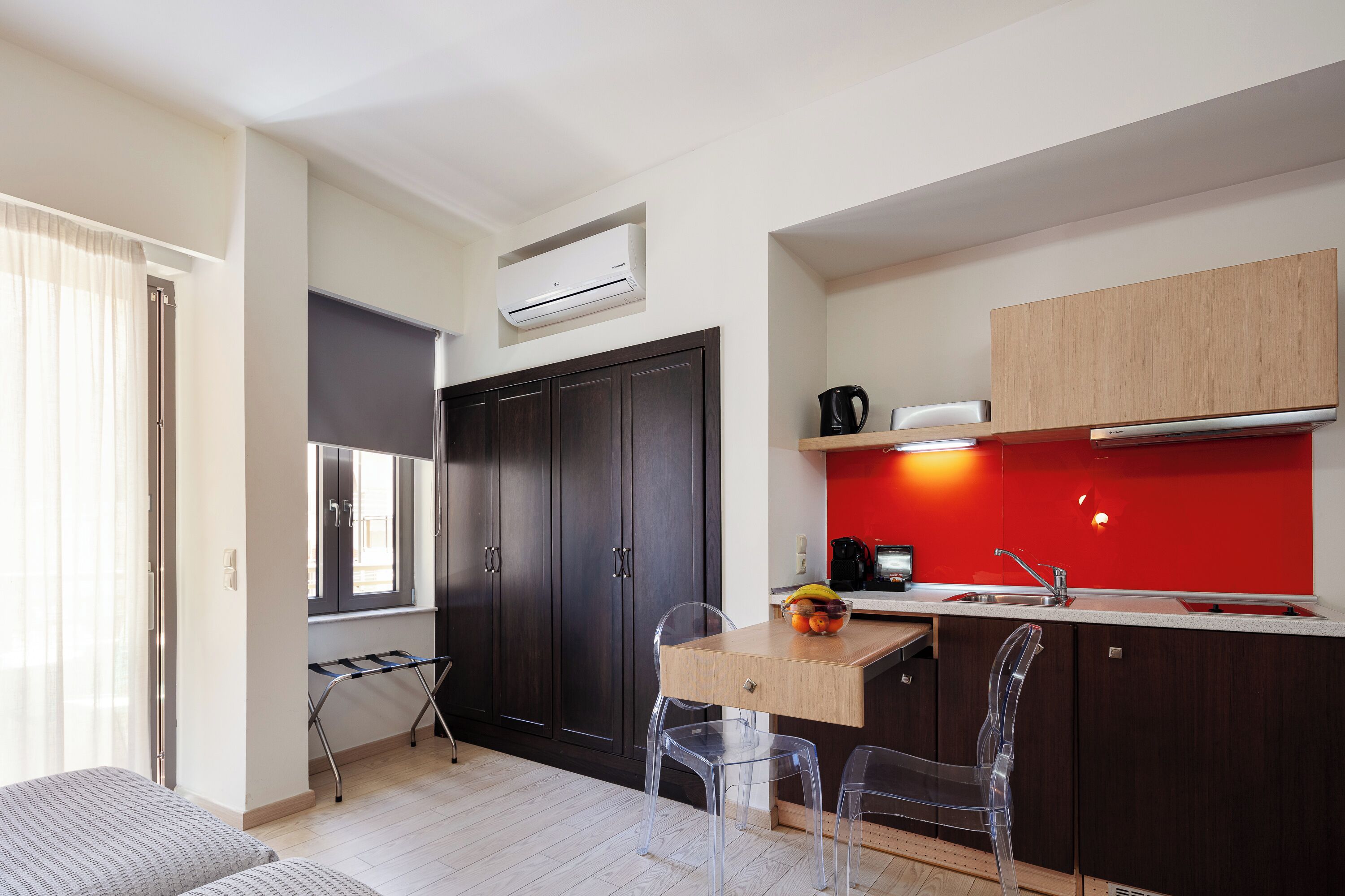 A compact kitchen with a wooden countertop, a red backsplash, and a black cabinet.