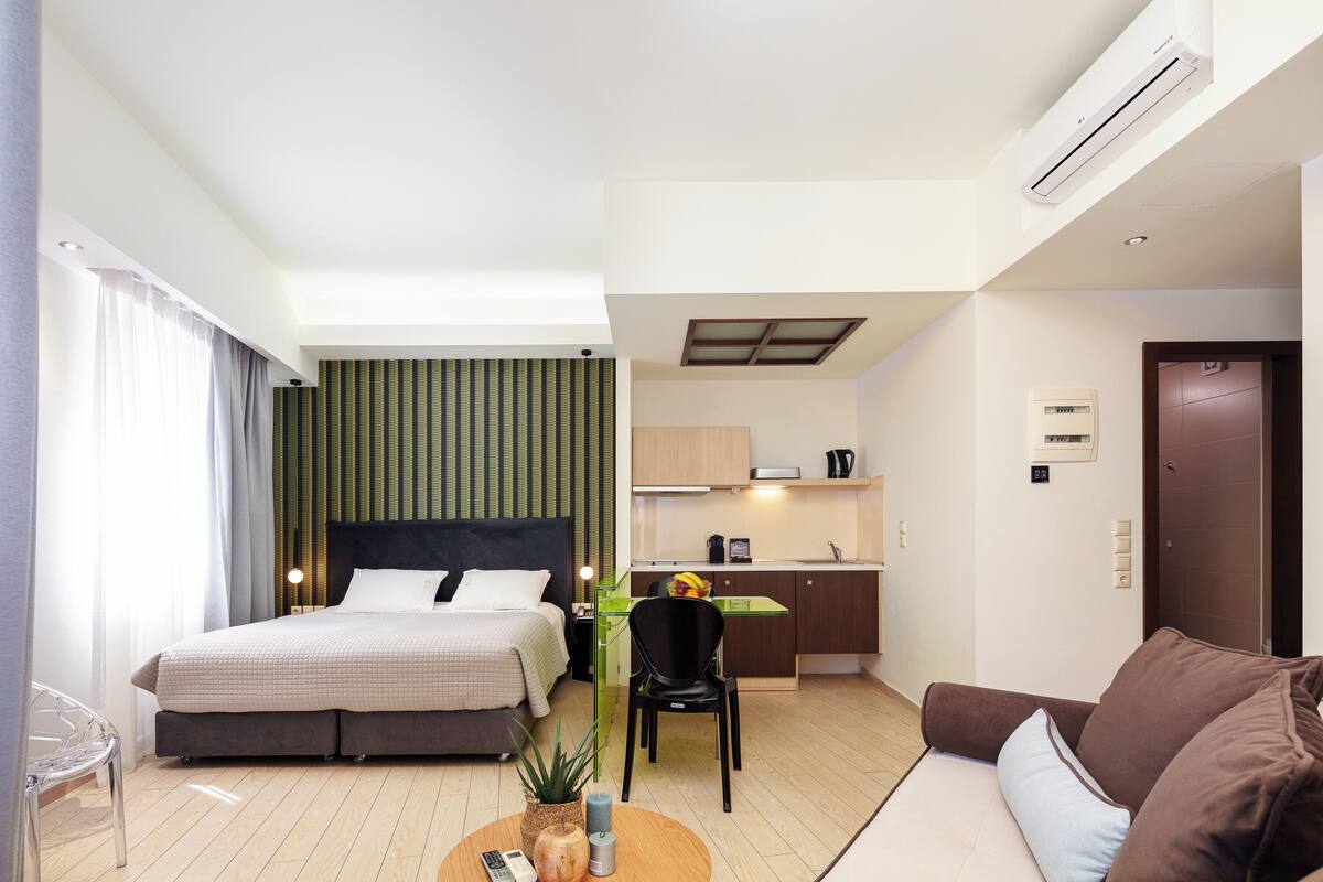 Une chambre d’hôtel comprenant un lit, un bureau, un canapé, une chaise et une petite table sur laquelle se trouvent une plante et une télécommande.