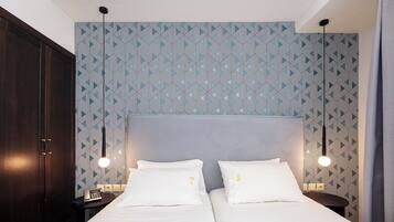 Una habitación de hotel con una cama grande, dos mesitas de noche y un papel tapiz estampado.