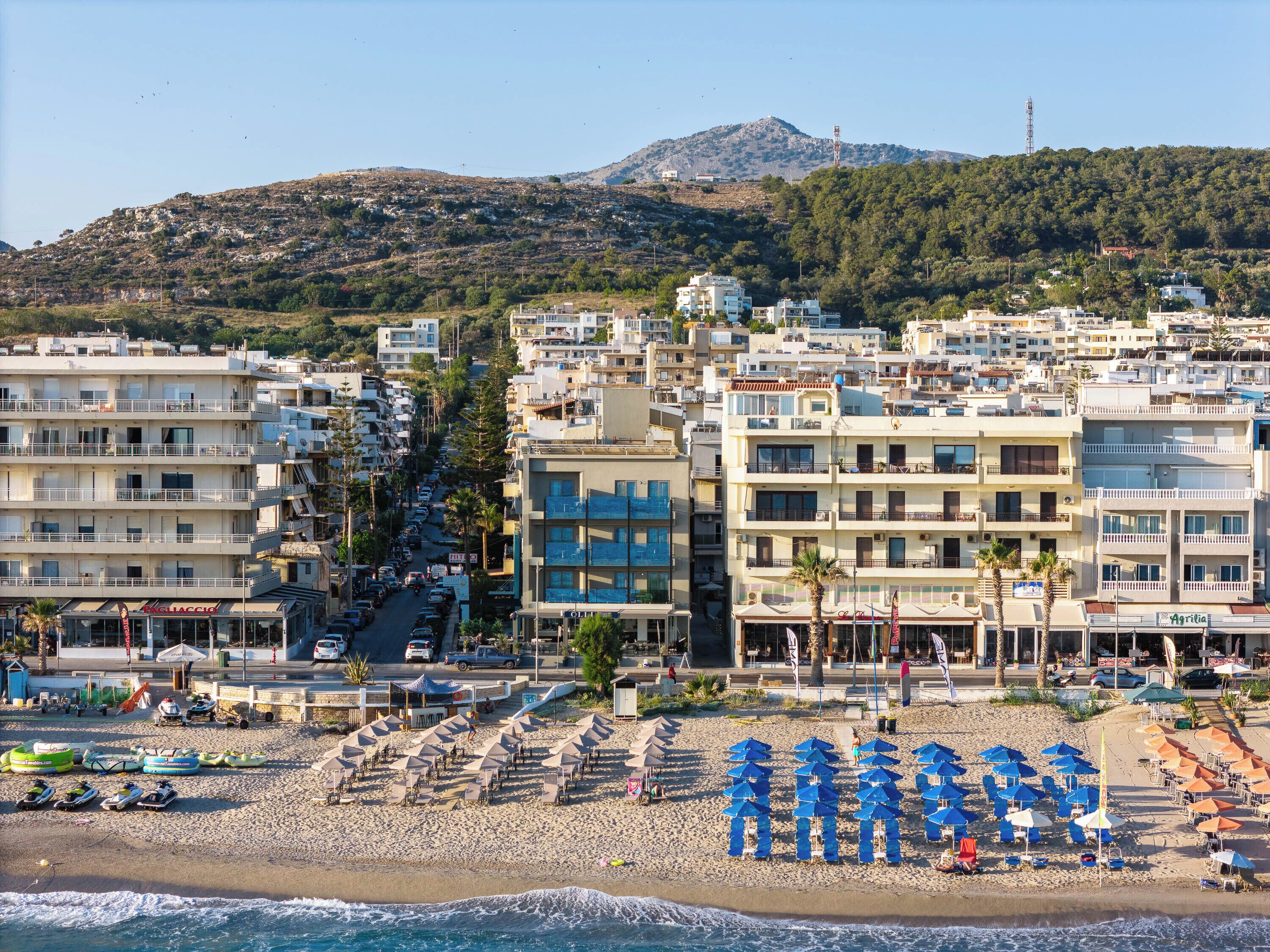 A coastal cityscape with a beach, buildings, and a mountain in the background.