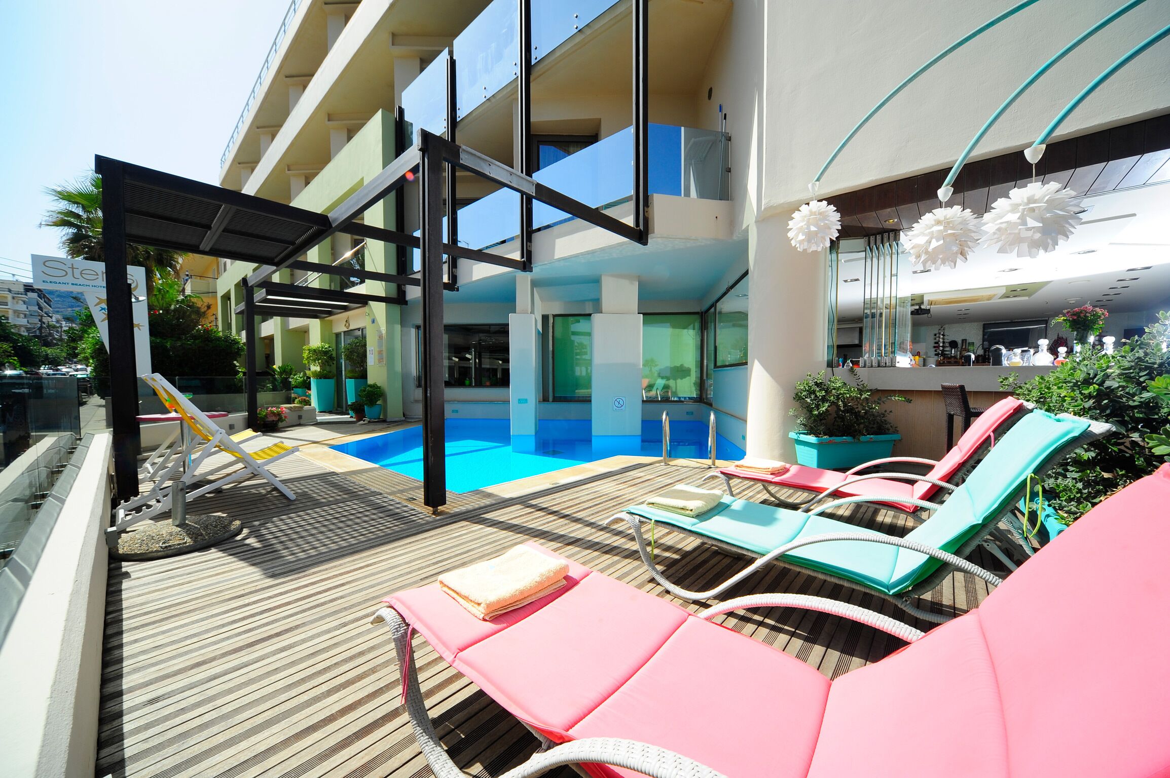 A rooftop pool area with lounge chairs, a slide, and a view of the building's interior.