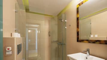 Un baño moderno con cabina de ducha de vidrio, lavamanos blanco y espejo con marco decorativo.