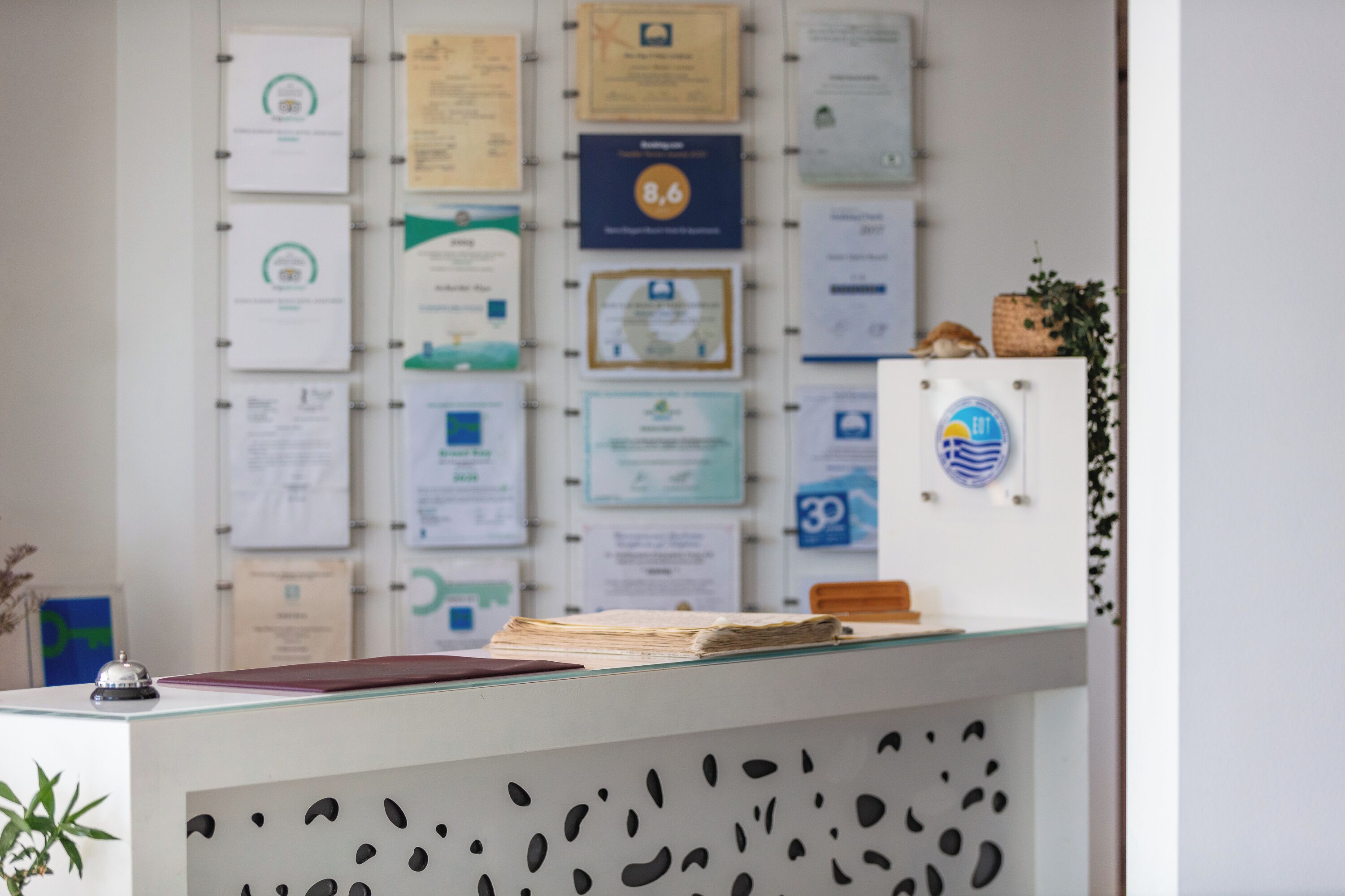 Un mostrador de recepción con encimera de vidrio, rodeado de certificados y premios enmarcados en la pared.