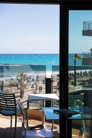 Ein Café am Strand mit Terrassenplätzen, Blick aufs Meer und Strandsonnenschirmen.
