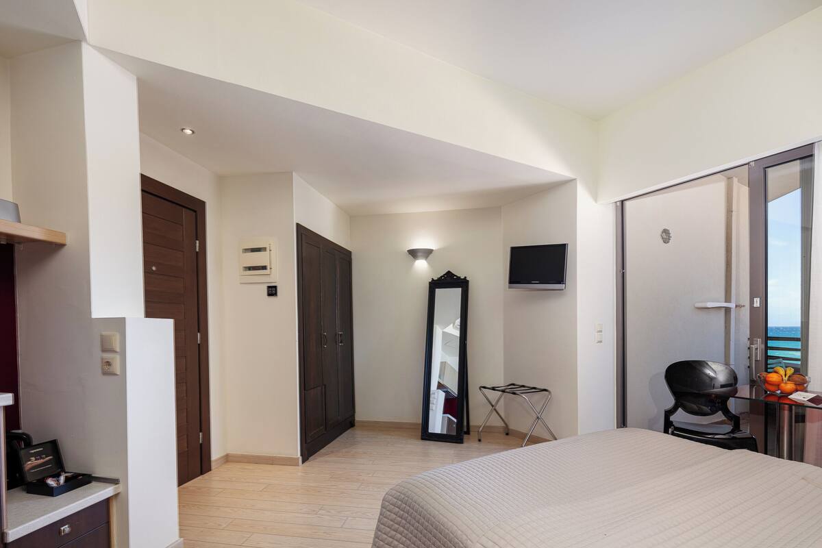 Une chambre d’hôtel avec un lit, une armoire, un miroir, une télévision et une petite table avec des fruits.