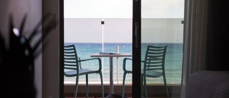 A balcony with a table and two chairs, overlooking the ocean.