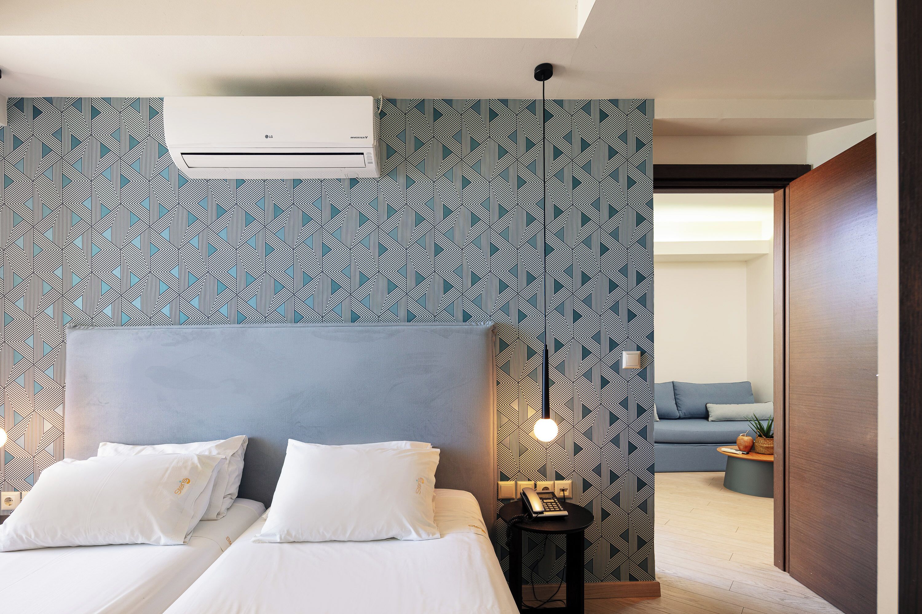 Et moderne hotelværelse med en stor seng, et sengebord med lampe og udsigt til opholdsområdet.