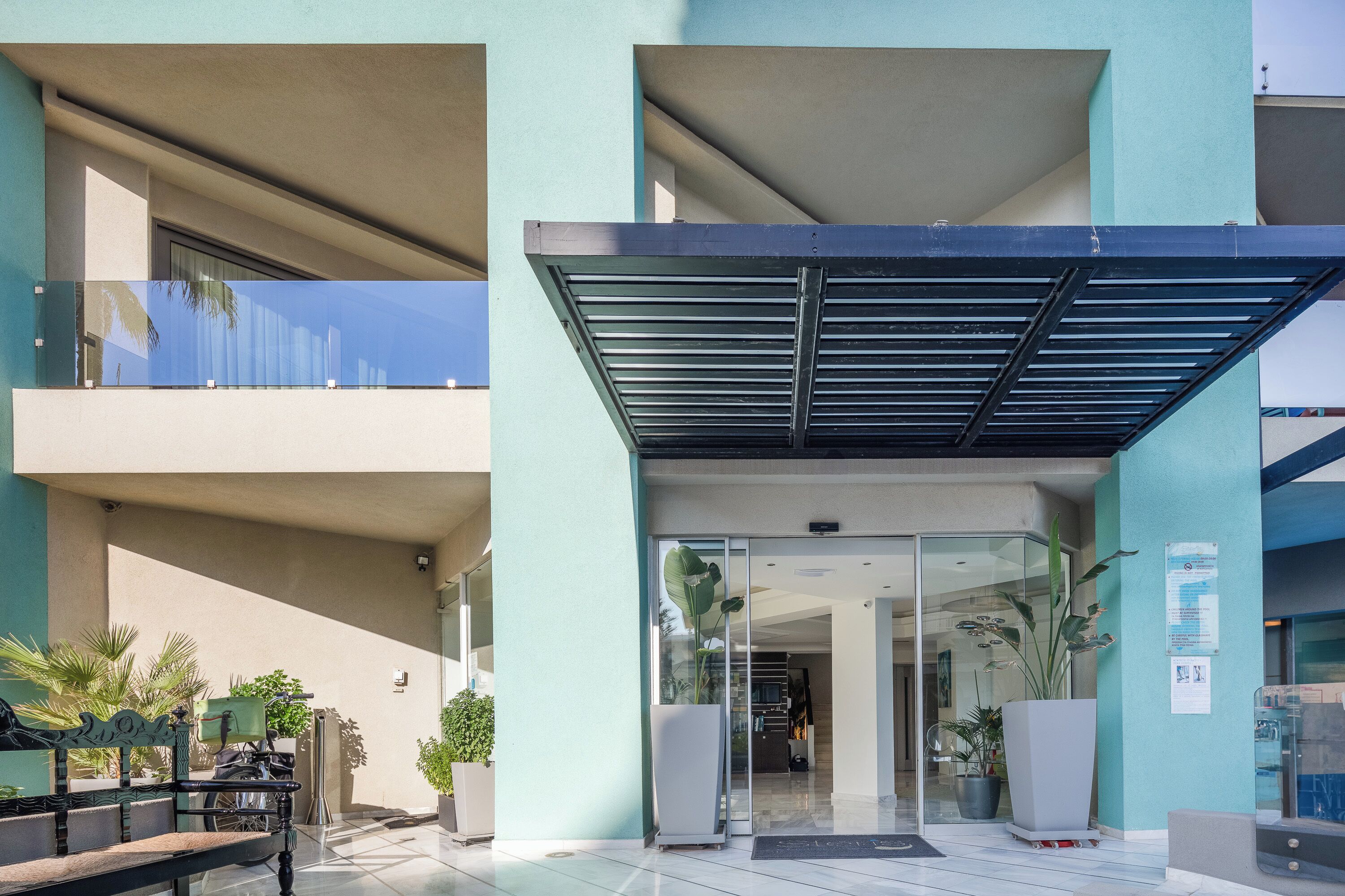 A modern building with a covered entrance, glass doors, and potted plants.