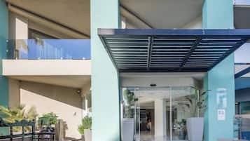 A modern building with a covered entrance, glass doors, and potted plants.