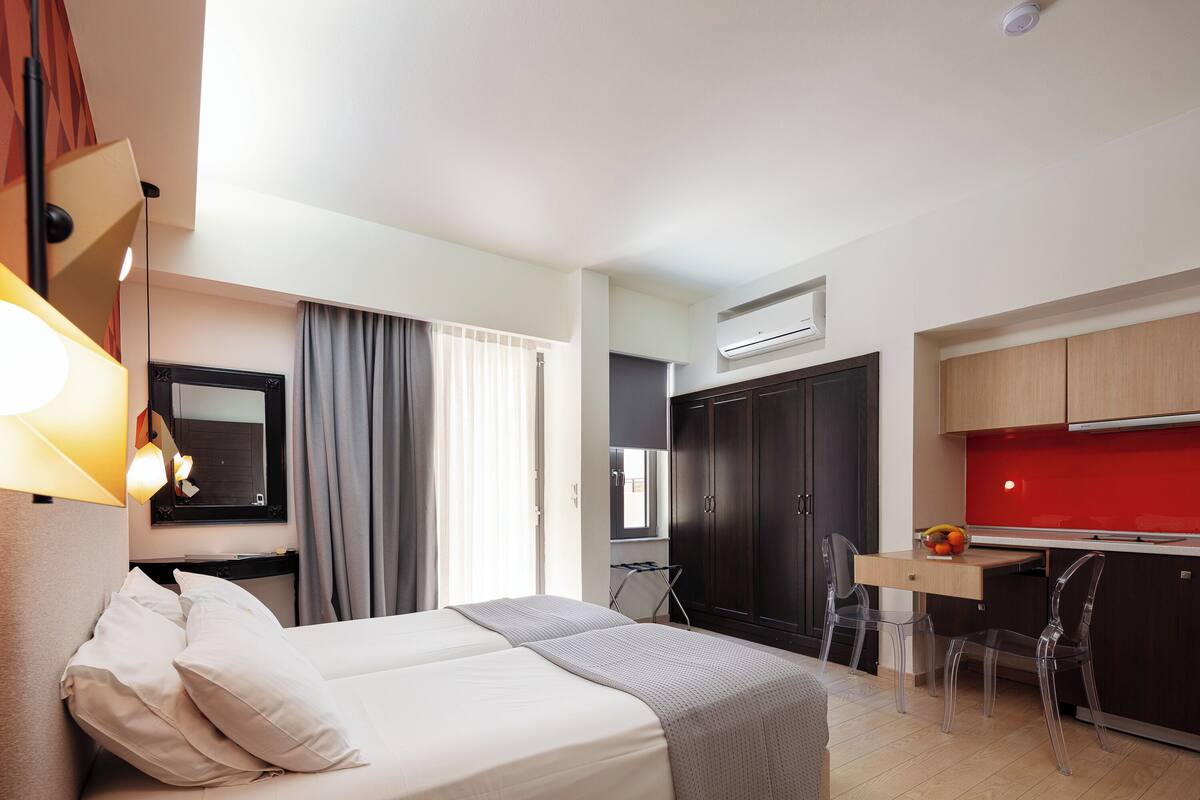 Une chambre d’hôtel équipée d’un lit, d’un bureau, d’une chaise, d’une armoire et d’un appareil de climatisation.