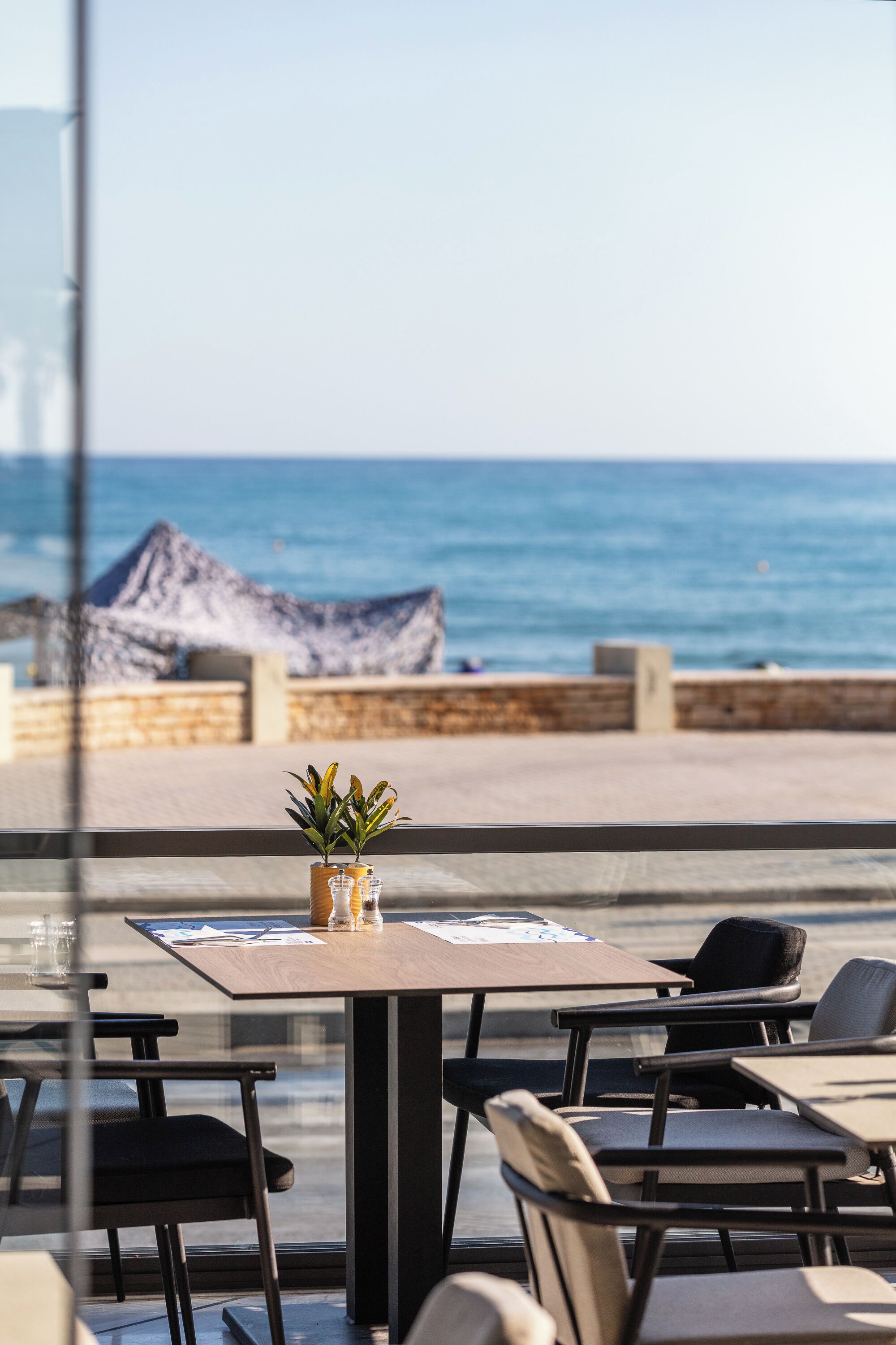 A seaside restaurant with outdoor seating, a wooden table, and a view of the ocean.