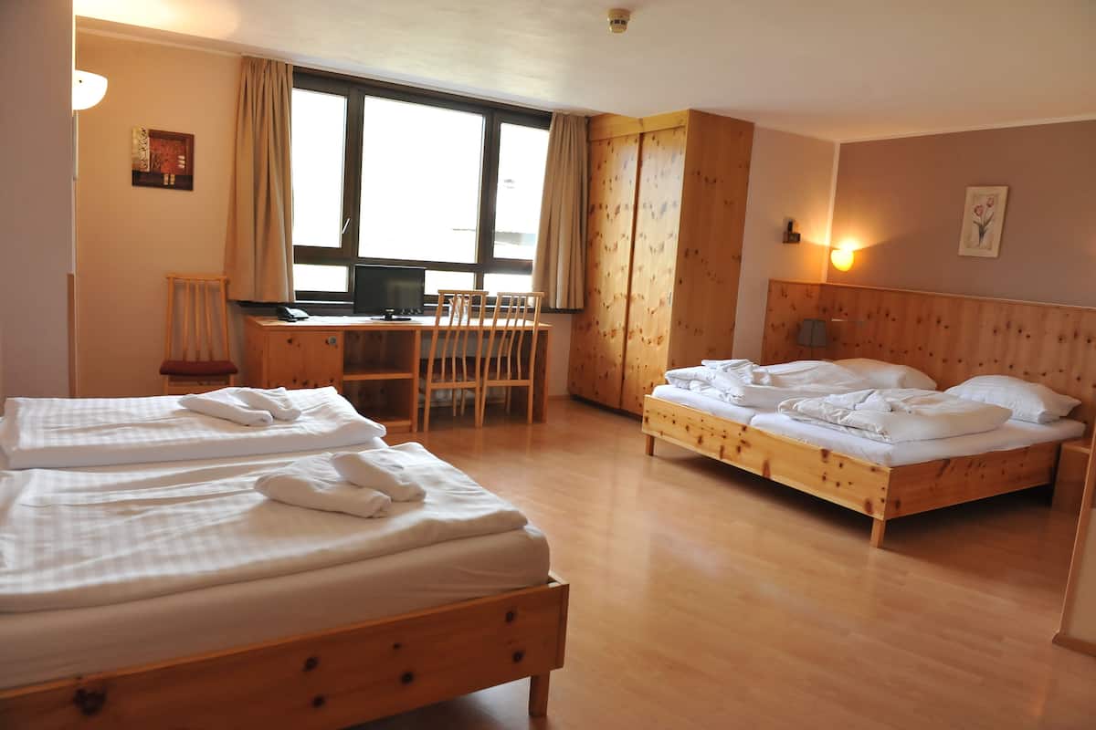 A hotel room with two beds, a desk, a chair, and a large window.