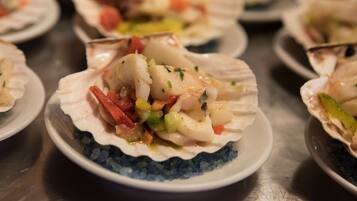 A seafood dish served in a scallop shell on a plate with a blue rim.