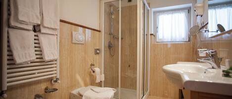 A modern bathroom with a glass-enclosed shower, a white sink, and a toilet.