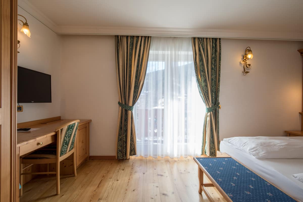 Una habitación de hotel con un escritorio de madera, una cama y un televisor.