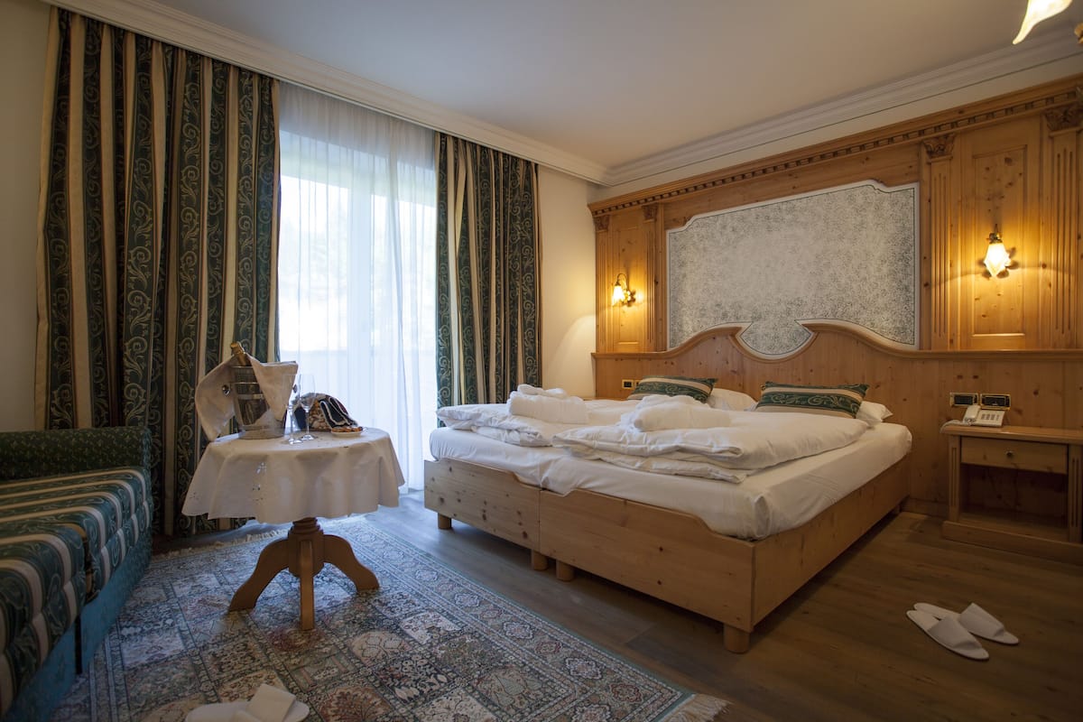 Un dormitorio ordenado con una cama grande, una mesita pequeña, una silla y una mesita de noche.