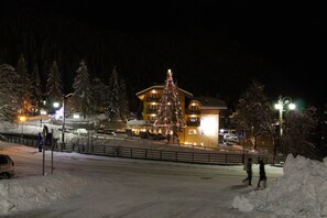 A hotel with a large Christmas tree in front, surrounded by snow-covered trees and a snow-covered ground. - Hotel Chalet all'Imperatore (Tre Ville)