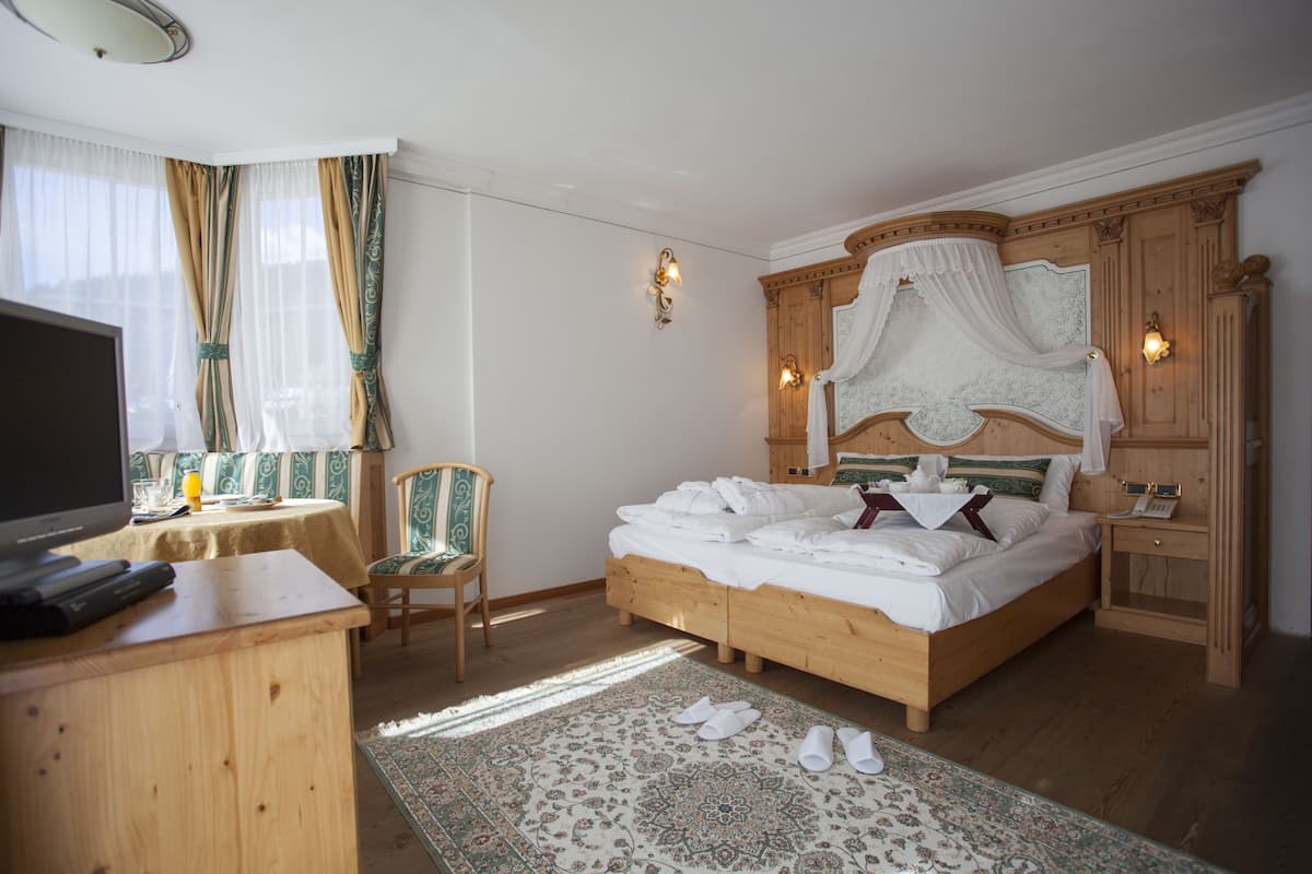 Una habitación de hotel con una cama de madera, televisión, escritorio y una silla.